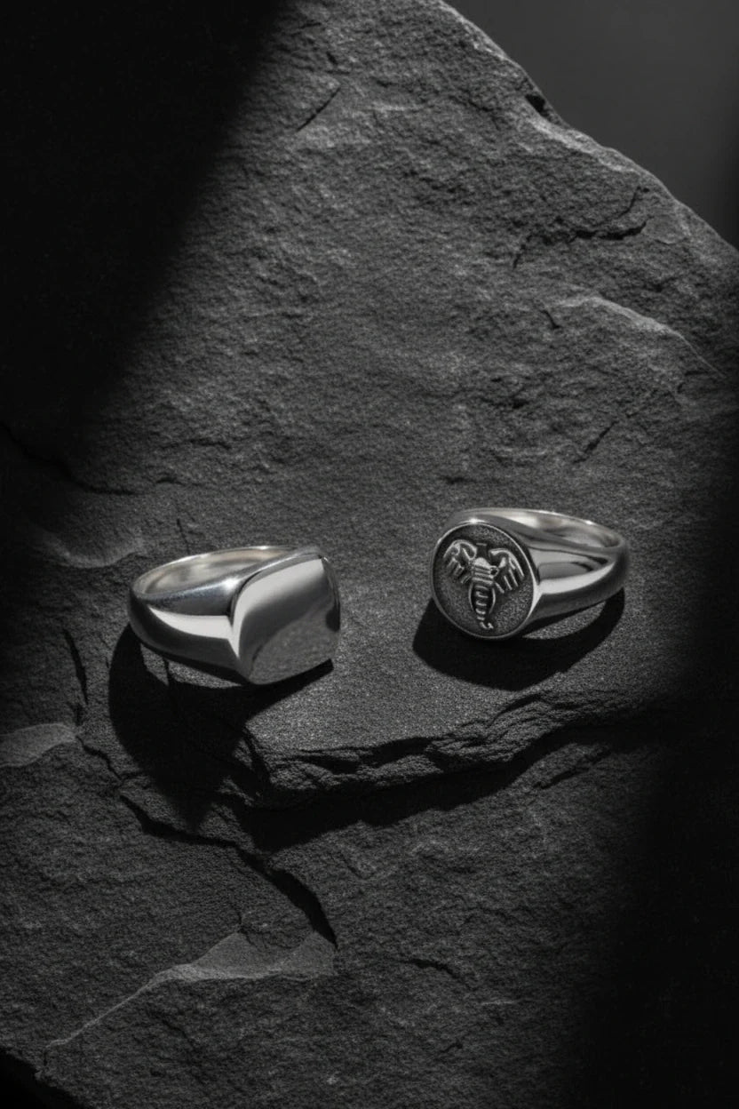 sterling silver men's signet rings on dark stone background.