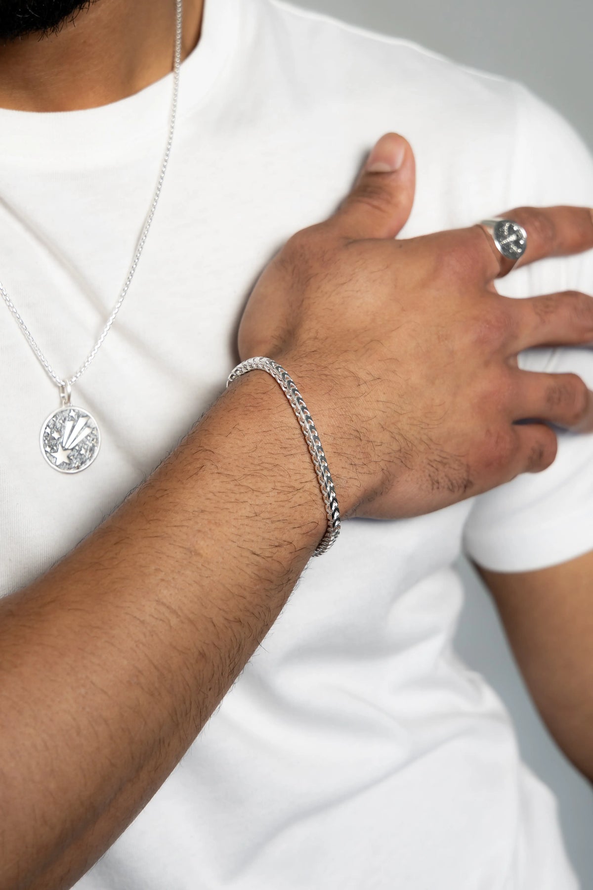 Men's silver bracelet, pendant necklace and ring styled with a white shirt