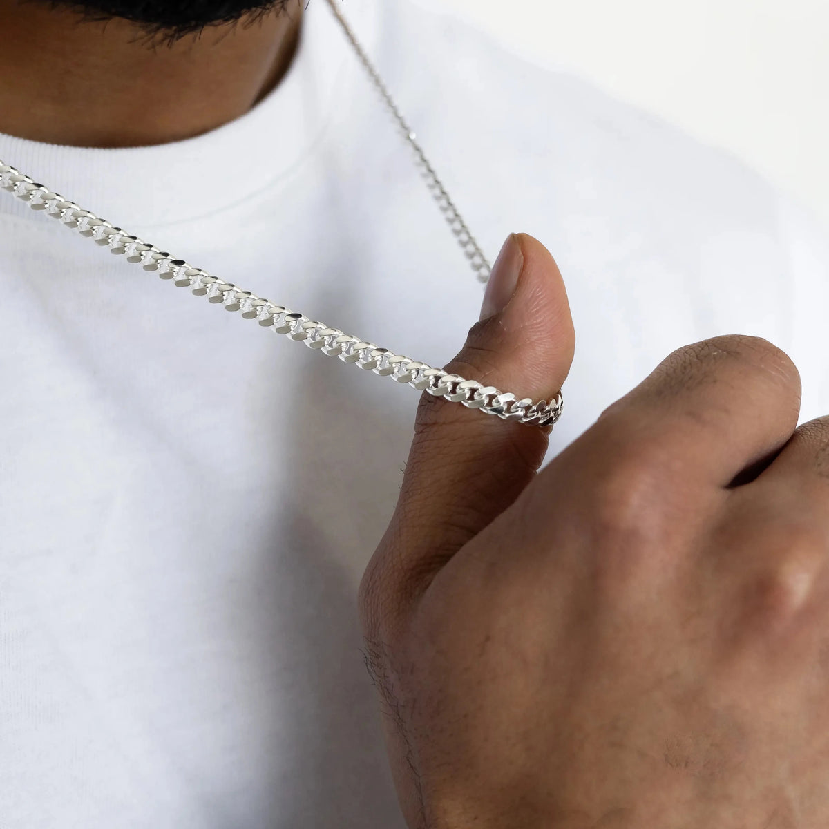 Close-up of a men's sterling silver Cuban chain worn with a white shirt